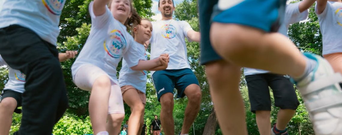 Joyful group of children and adult engaging in playful activities in a sunny park setting.